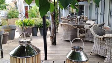 A wooden deck with wicker furniture and metal lanterns.