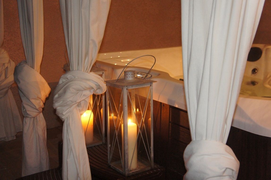 A spa room with a bathtub, a candle, and a lantern.