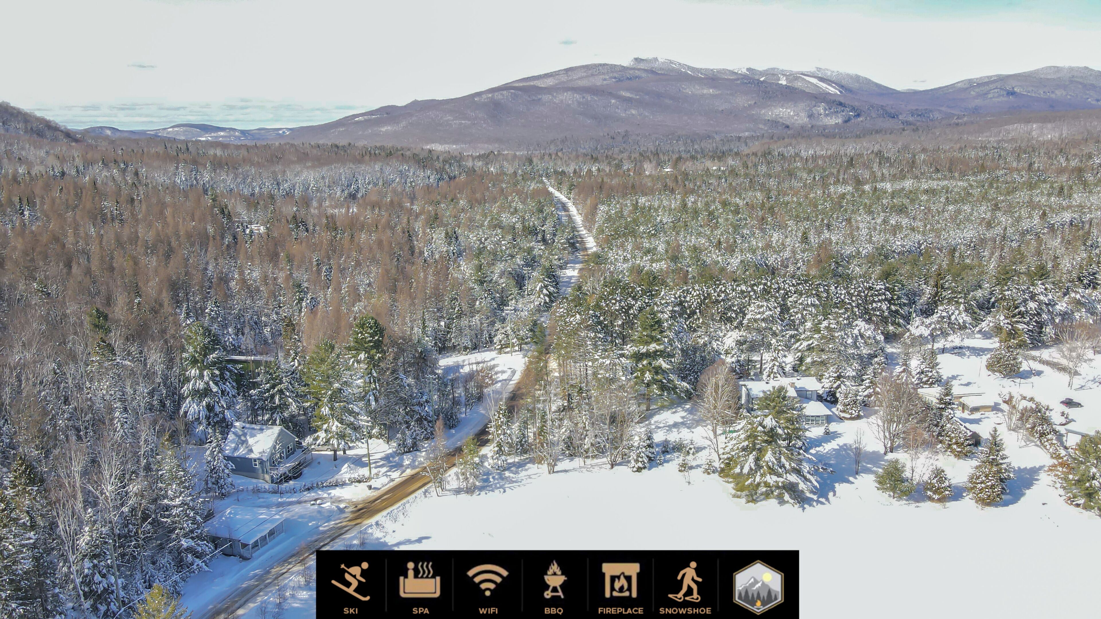 Un paysage enneigé avec une station de ski, comprenant des pistes de ski, une cheminée et une icône représentant des raquettes à neige.