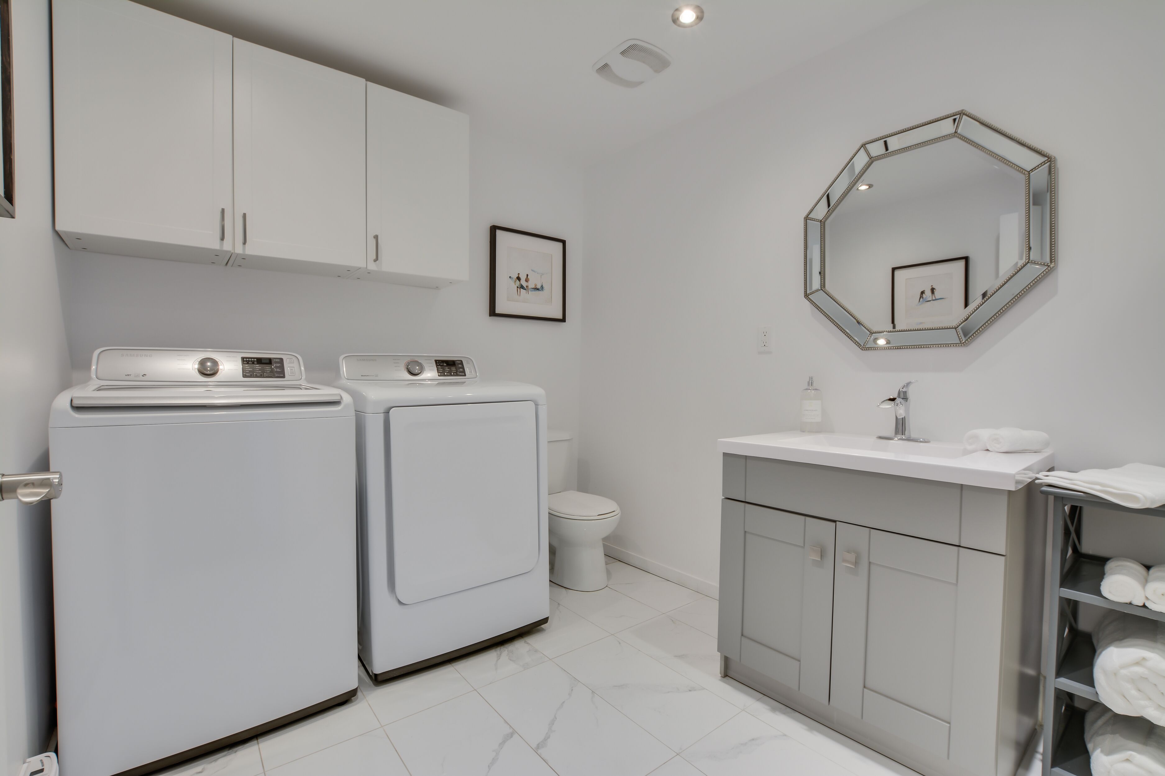 Un baño moderno con lavadora y secadora integradas, un tocador con espejo y un perchero para toallas.