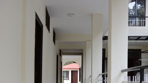 A corridor with marble flooring, white walls, and a red door at the end. - The Kings Kalindi Resort & Spa (Dhanaulti)