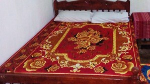 Ein Bett mit einer roten und goldenen Bettdecke, einem Holzkopfstück und weißen Kissen.