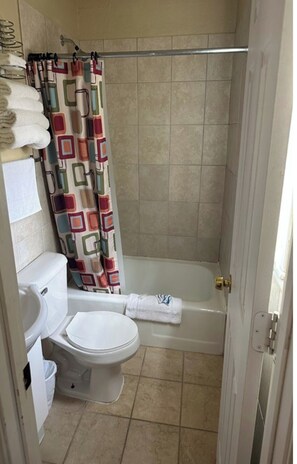 A small bathroom with a toilet, a bathtub, and a shower curtain.