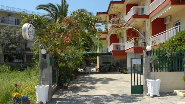 A courtyard with a building entrance, potted plants, and a sign indicating a parking area. - Anestis Apartments (Kavala)