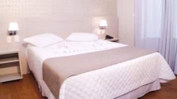 Una habitación de hotel ordenada con cama, mesitas de noche y un velador.