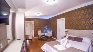 Ein Hotelzimmer mit einem großen Bett, einem Fernseher, einem Schreibtisch und einem Sessel.
