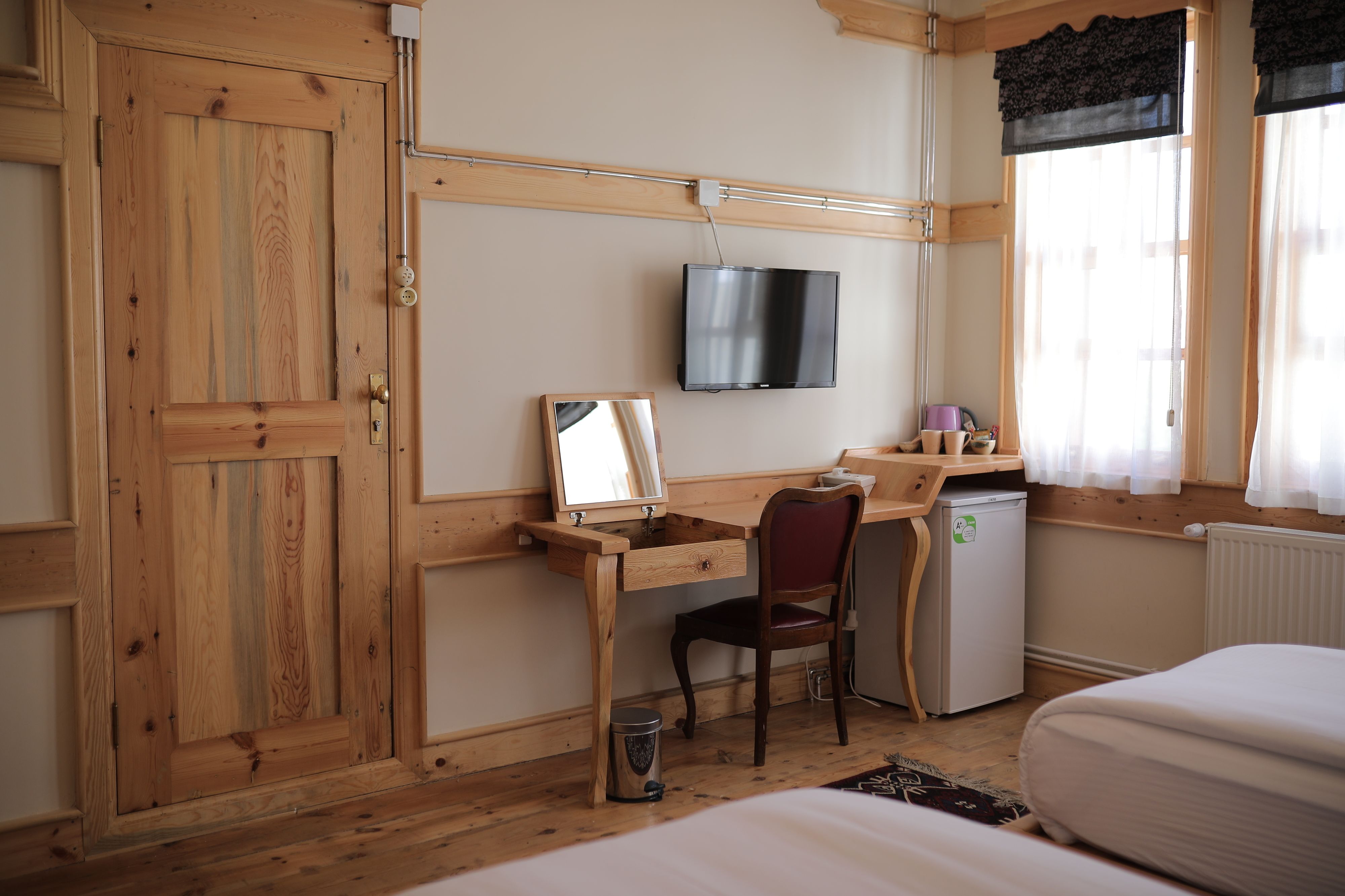 Una habitación de madera con escritorio, silla, televisor y cama.