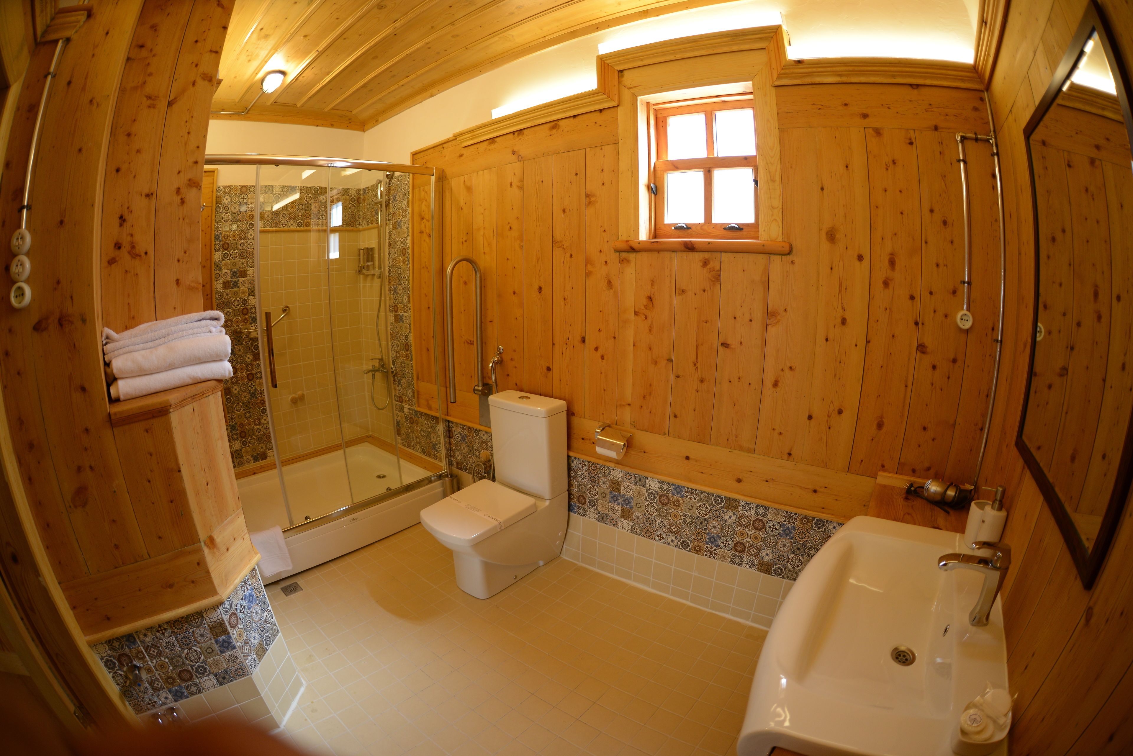 Une salle de bain en bois avec une douche en verre, des toilettes et un lavabo.