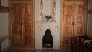 A room with wooden double doors, a fireplace with candles, and a chair. - Melekli Konak (Amasya)