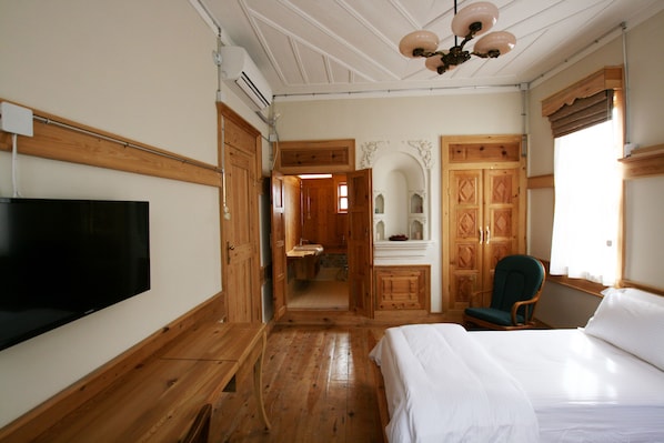 A wooden-floored room with a bed, a television, and a chair. - Melekli Konak (Amasya)