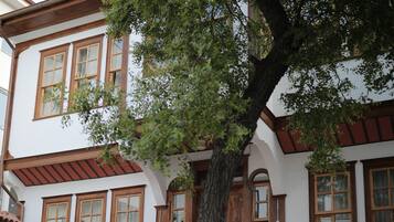 Un edificio tradicional con una escalera, muebles de madera y un árbol en el patio.