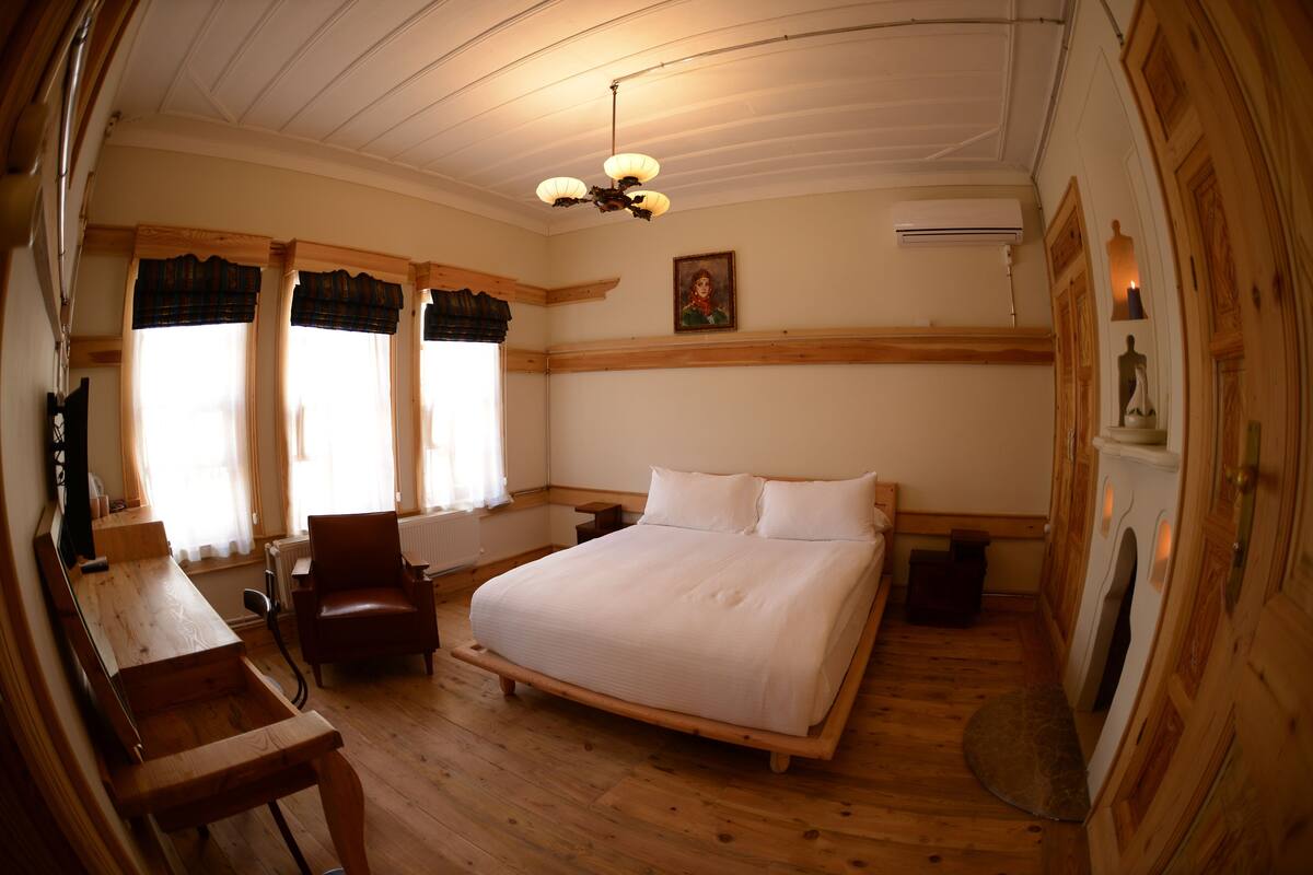 A wooden-framed bedroom with a bed, a chair, a desk, and a radiator.