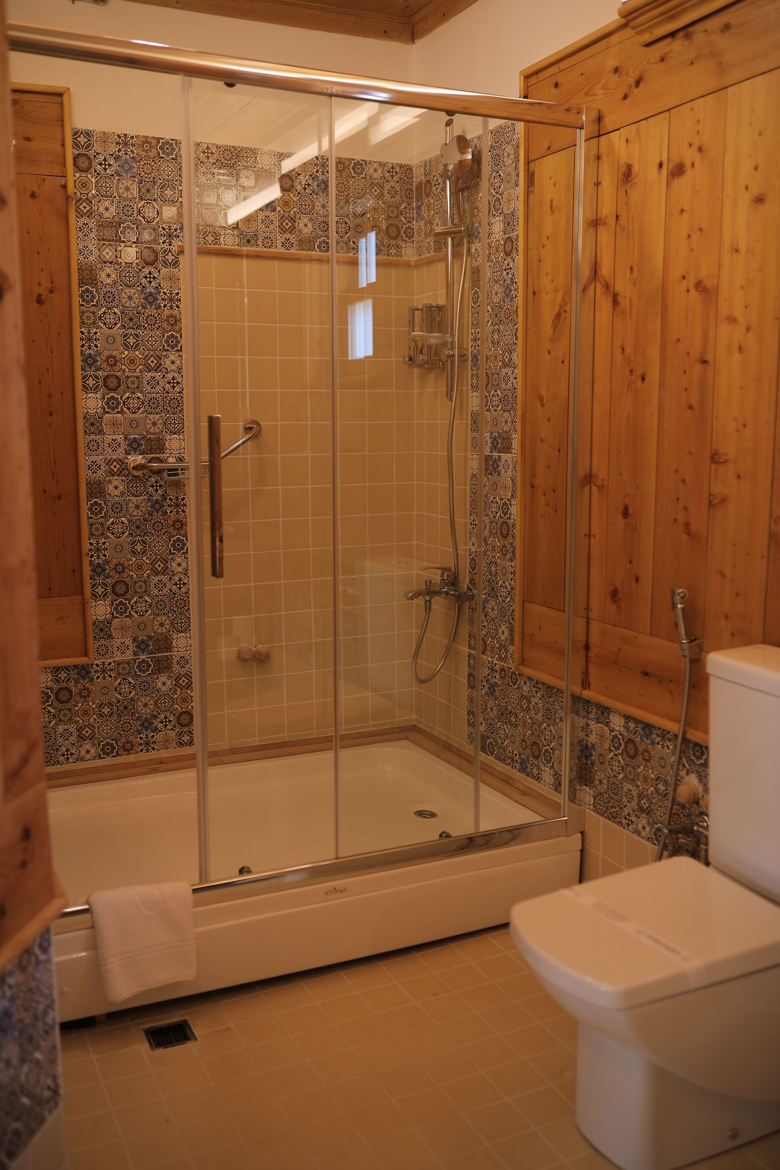 A shower area with a glass door, a bathtub, and a toilet.