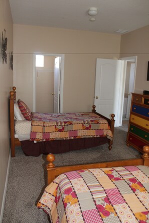 A bedroom with a wooden bed, a dresser, and a door leading to another room. - Tuscan Hills Rentals (Davenport)