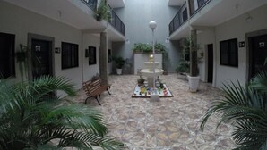 A spacious indoor courtyard with a central fountain, potted plants, and a bench. - Pousada Golden House (Aguas de Sao Pedro)