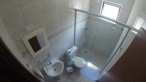 A bathroom with a glass shower enclosure, a toilet, and a sink. - Pousada Golden House (Aguas de Sao Pedro)