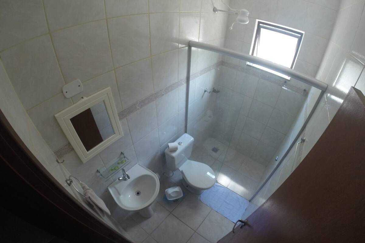 A bathroom with a glass shower enclosure, a toilet, and a sink.