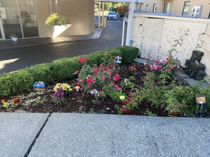 A landscaped garden area with various flowers and a welcome sign. - Auburn Motel (Auburn)