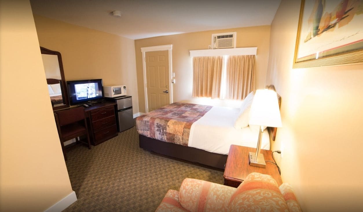 Ein Hotelzimmer mit einem Bett, einem Schreibtisch mit Computer, einer Mikrowelle und einem Fernseher.