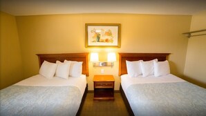 Habitación de hotel con dos camas, una mesita de noche con lámparas y un cuadro enmarcado en la pared.