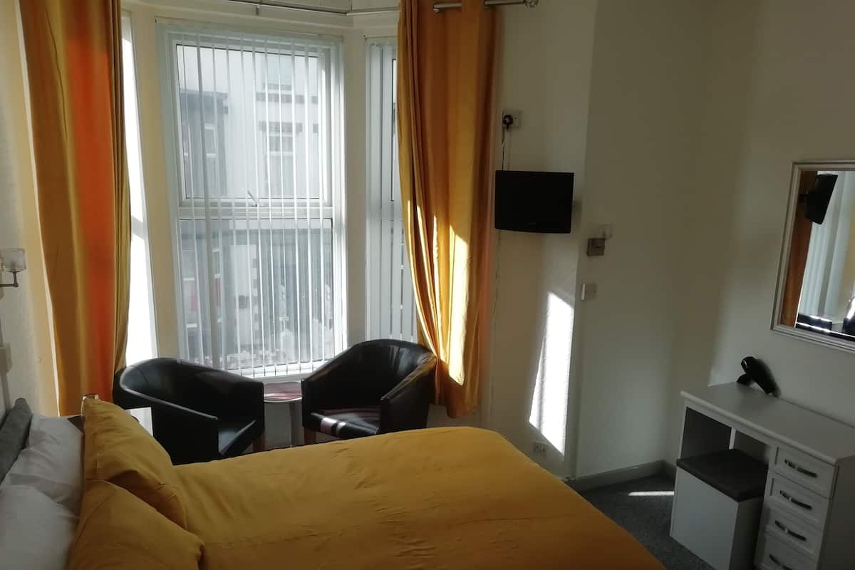 A hotel room with a bed, a desk, a chair, and a TV.