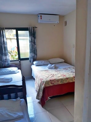 A small, clean room with a bed, a chair, and a window. - Pousada Flor Amarela (Balneário Camboriú)