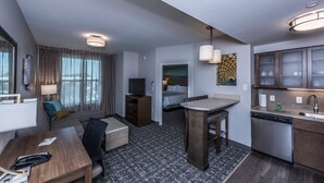 A compact hotel room with a kitchenette, a sofa, a dining table, a bed, and a bathroom. - Staybridge Suites Charleston - Mount Pleasant by IHG (Mount Pleasant)