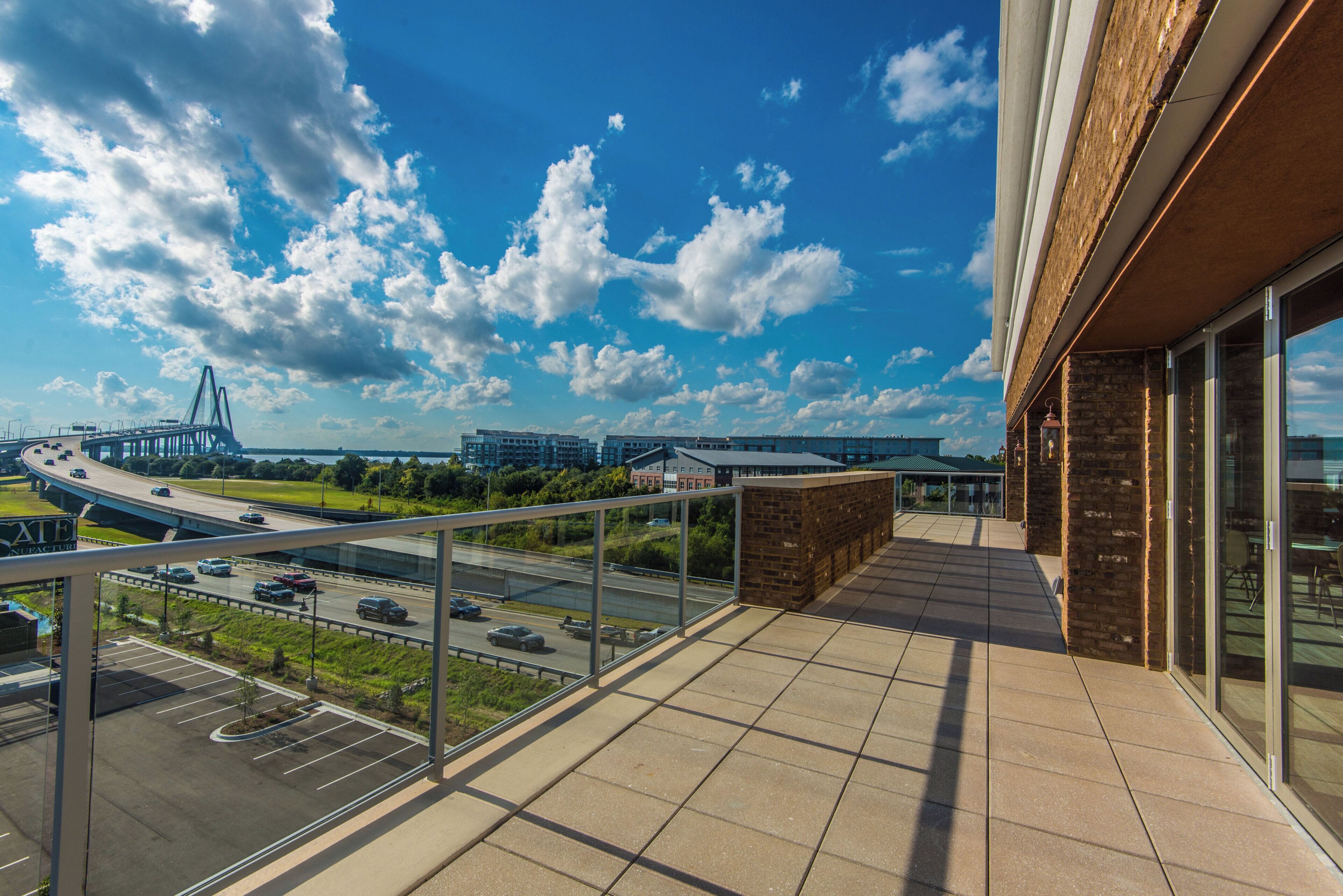 A balcony with a view of a highway, buildings, and a bridge.