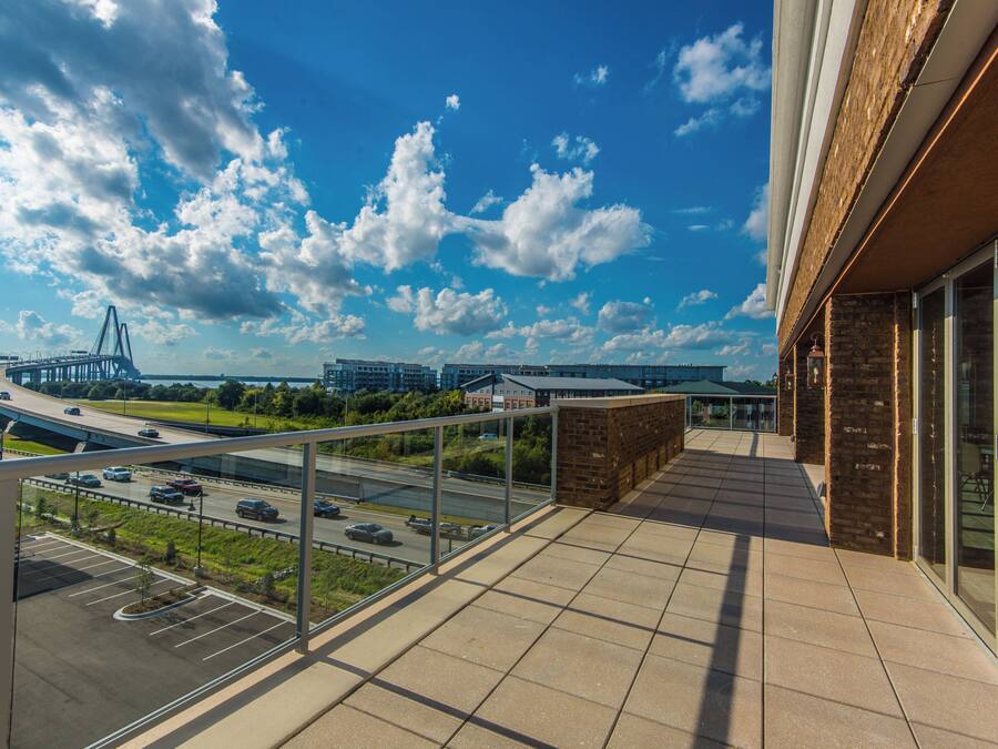 A balcony with a view of a highway, buildings, and a bridge.