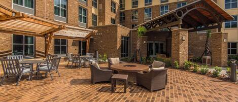 A courtyard with outdoor seating, a fire pit, and a covered area with a pergola.