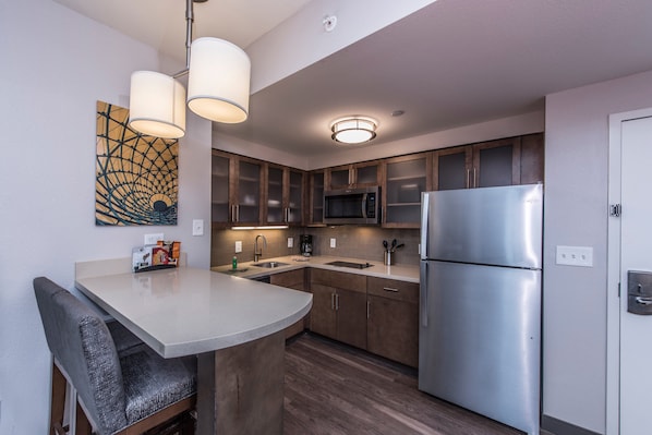 A modern kitchen with wooden cabinets, stainless steel appliances, and a bar area with seating. - Staybridge Suites Charleston - Mount Pleasant by IHG (Mount Pleasant)
