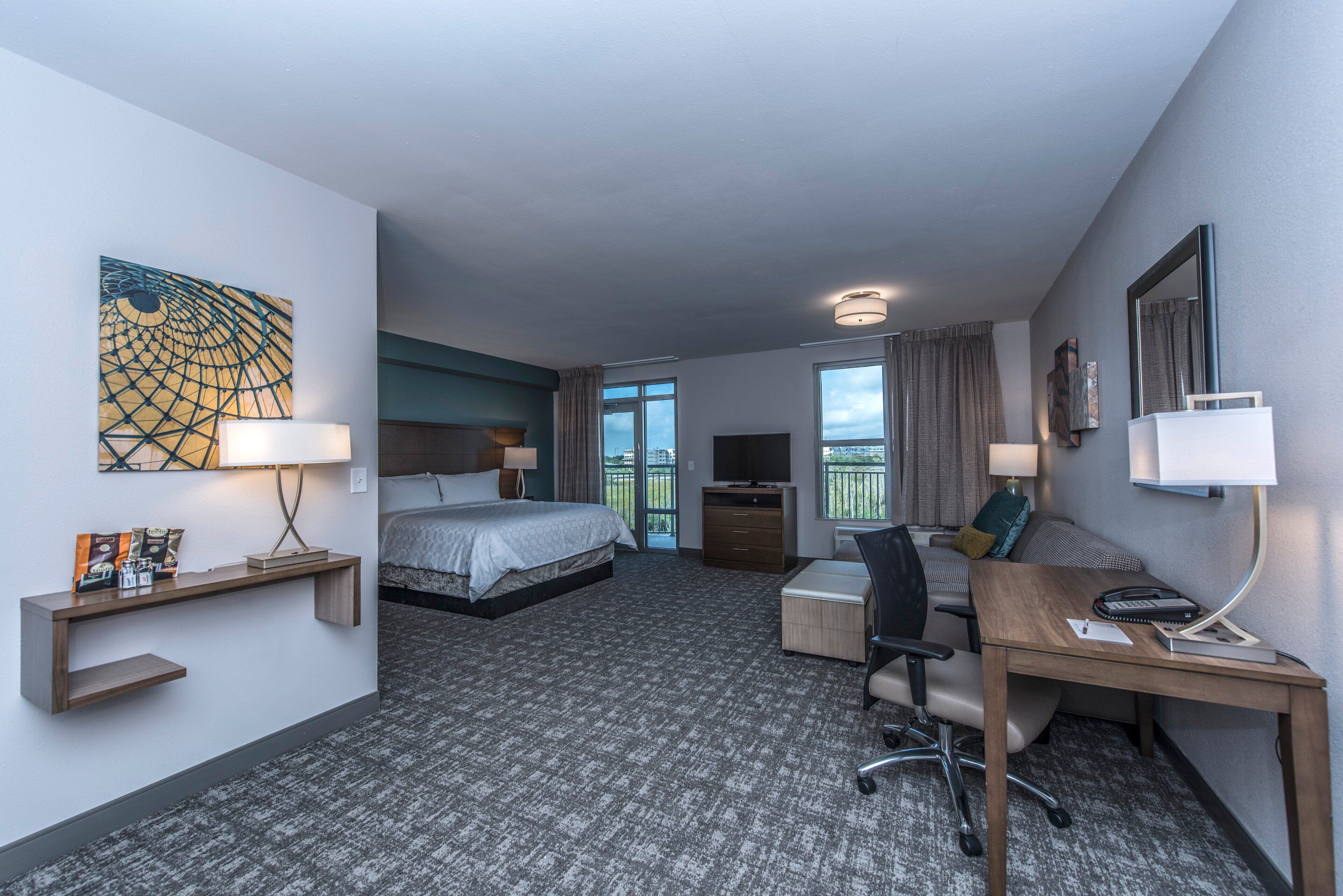 A hotel room with a bed, desk, chair, and a TV.