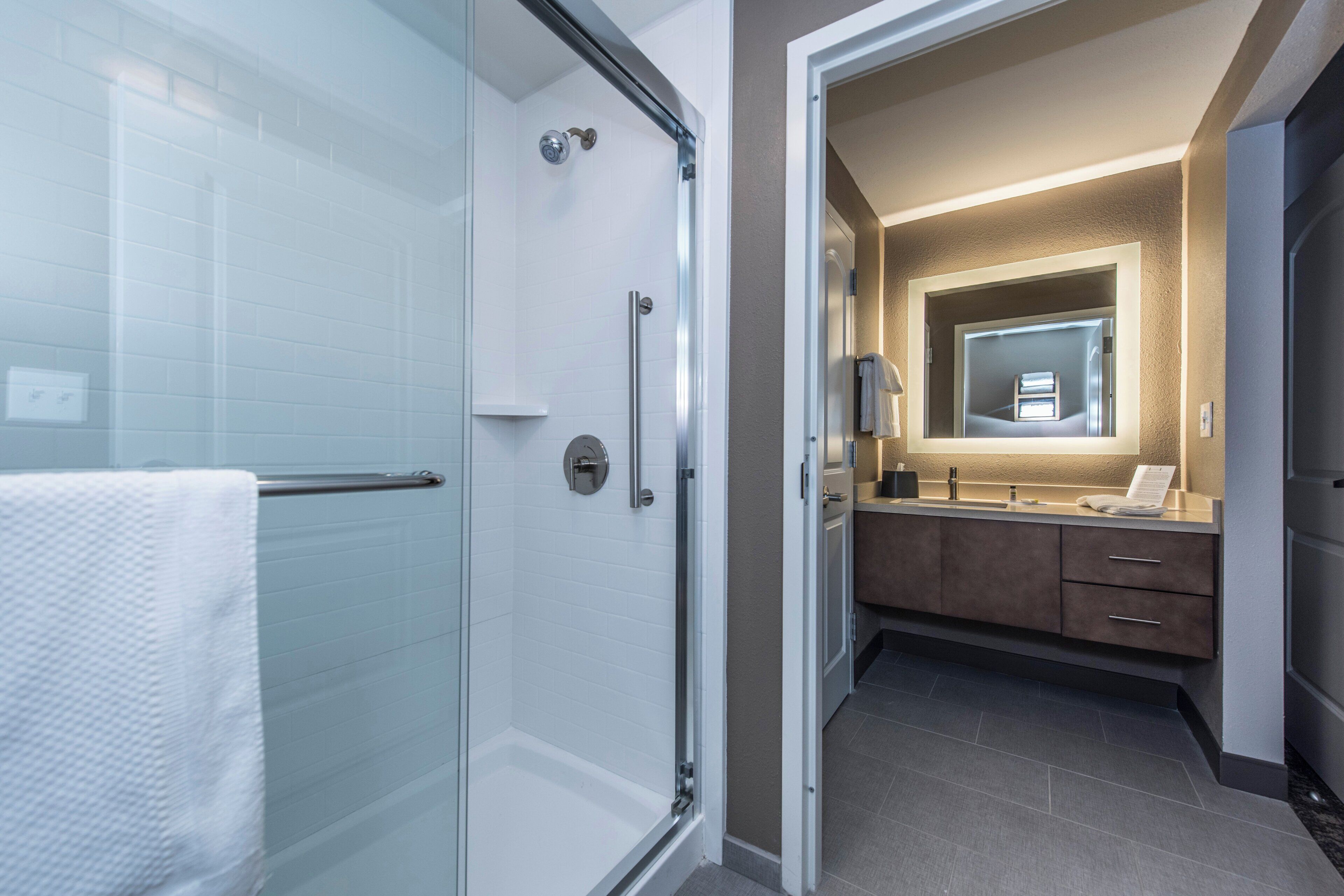 A modern bathroom with a glass shower enclosure, a vanity with a mirror, and a bathtub.