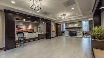 A spacious lobby with a reception desk, a stone fireplace, and a large window.