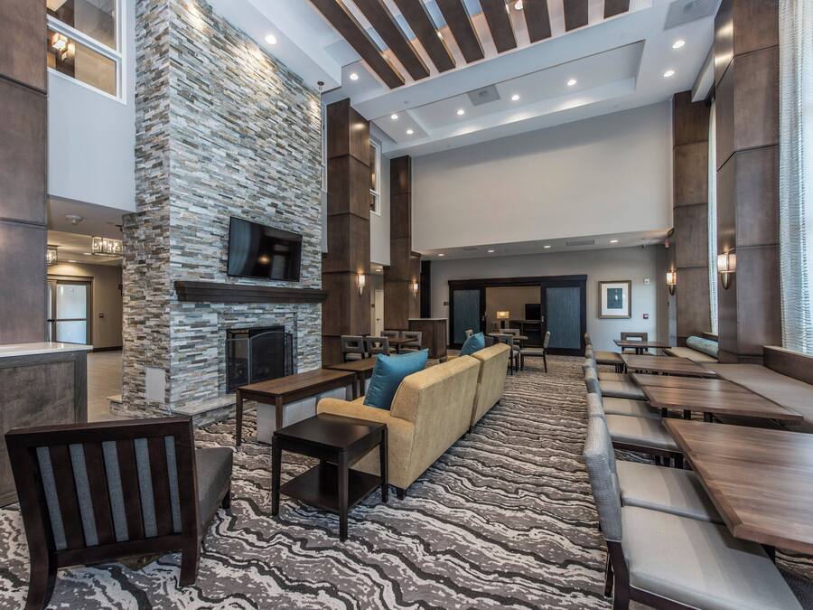 Ein großzügiger Lounge-Bereich mit Wandverkleidung aus Stein, einem Flachbildfernseher, verschiedenen Sitzgelegenheiten, darunter Sofas und Sessel, und einem gemusterten Teppich.