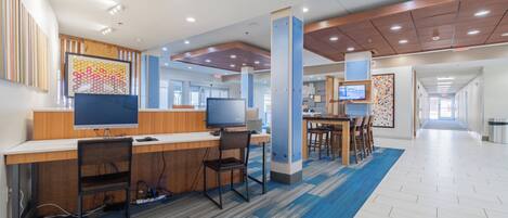 A modern hotel lobby with a reception desk, seating area, and a corridor leading to other rooms.