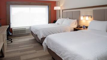 Una habitación de hotel con dos camas, un escritorio y un ventanal grande.
