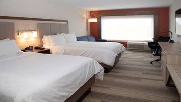 A hotel room with two beds, a desk, a chair, a lamp, and a large window.