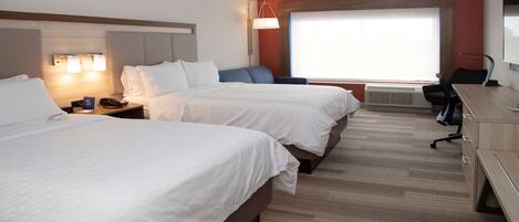 A hotel room with two beds, a desk, a chair, a lamp, and a large window.