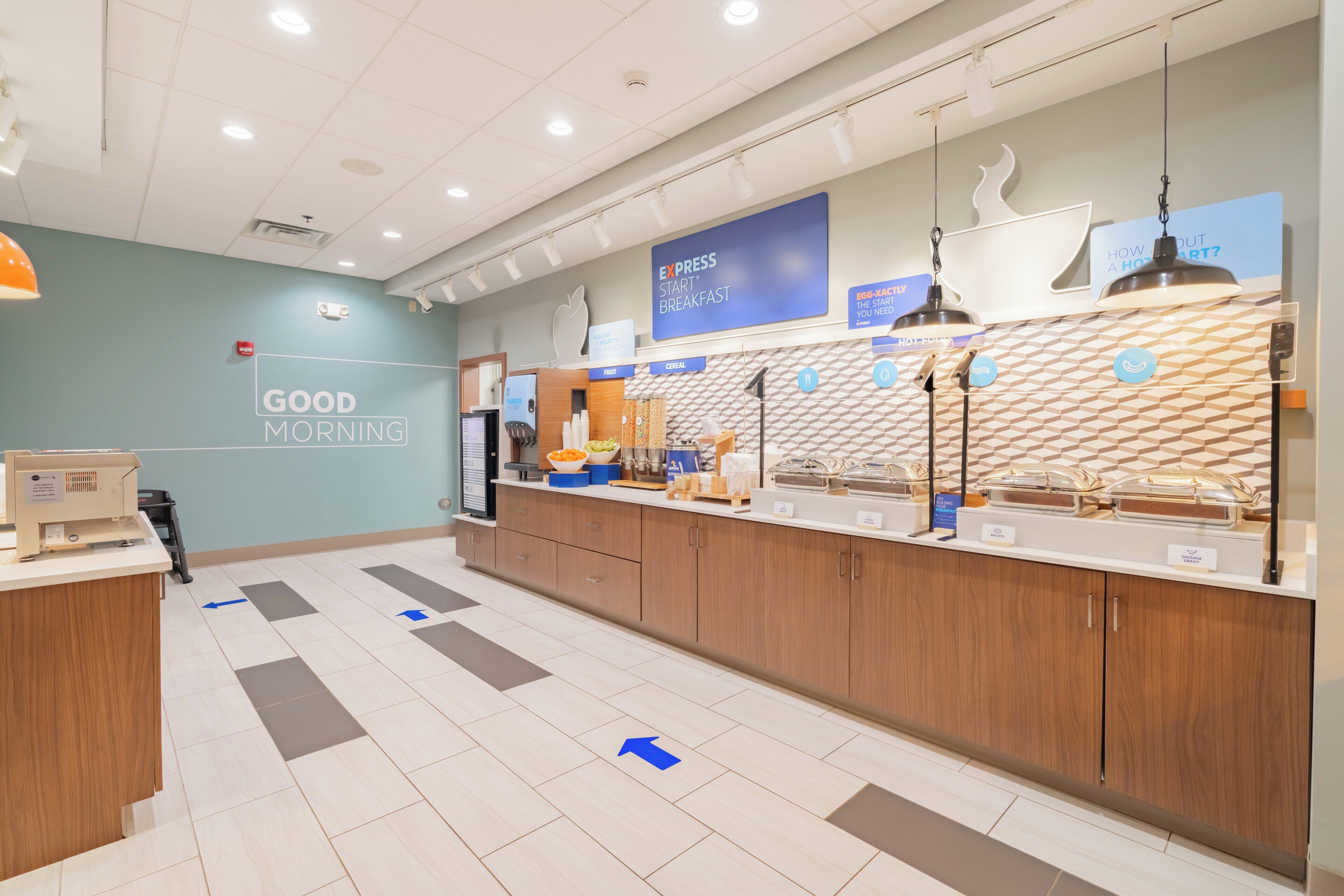 A modern breakfast area with a sign reading "GOOD MORNING" and a counter displaying various food items.