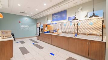 A modern breakfast area with a sign reading "GOOD MORNING" and a counter displaying various food items.