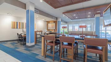 A modern hotel lobby with a central seating area, a reception desk, and artwork on the walls.
