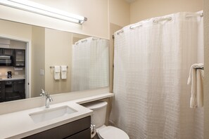 A bathroom with a sink, mirror, toilet, and shower curtain.