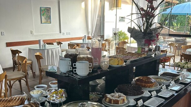 A buffet with various food items, a coffee station, and a large window with a view of greenery.