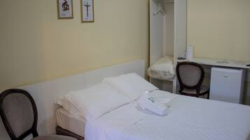 Una habitación de hotel con cama, una silla, un escritorio y un armario.