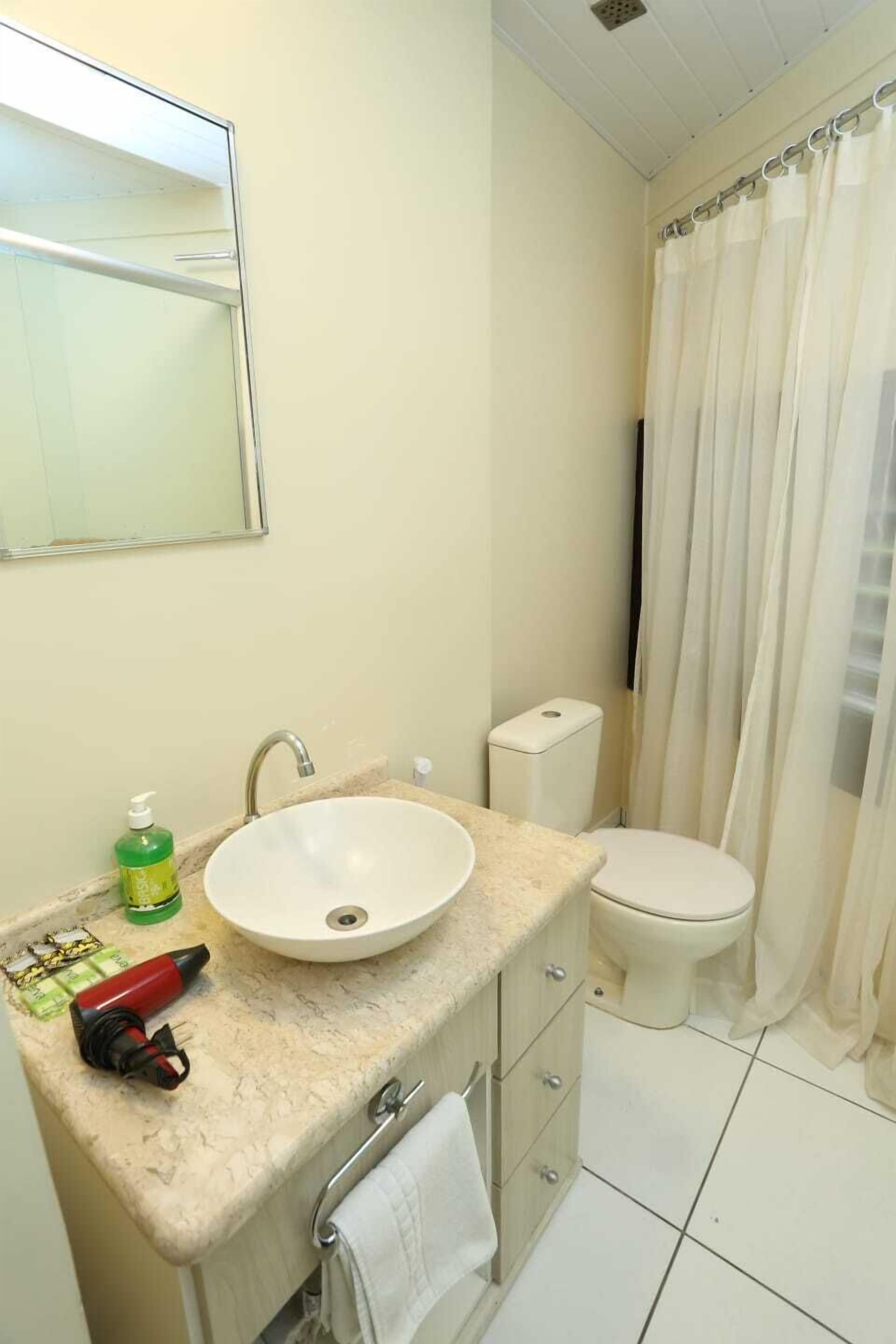 Un baño con lavamanos blanco, inodoro y cortina de ducha.
