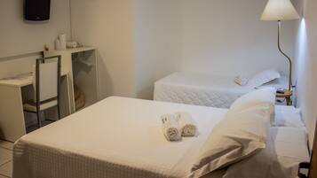Una habitación de hotel con cama, escritorio, silla, televisor y lámpara.