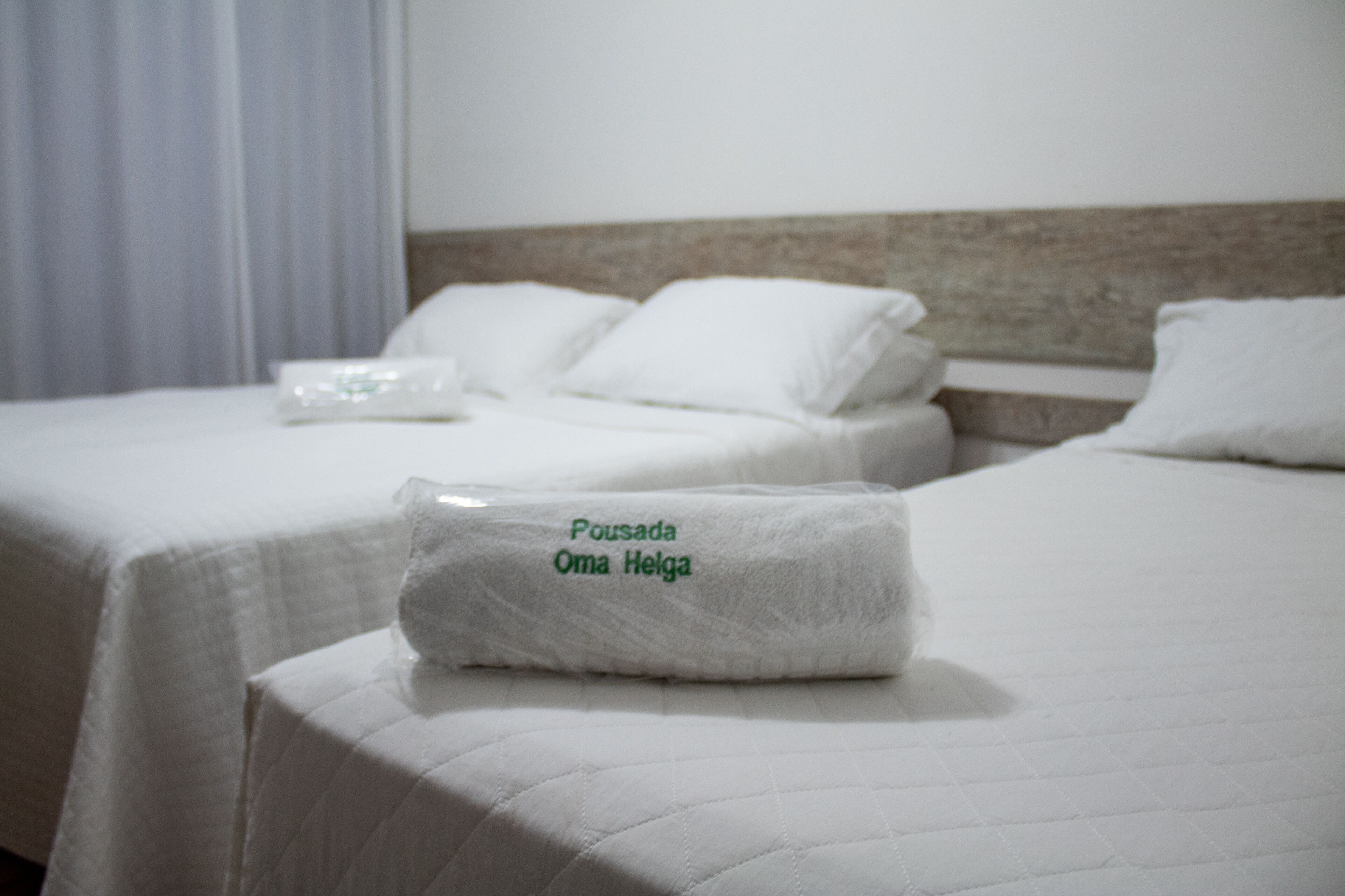 Two beds with white bedding and a neatly folded towel on the bed in the foreground.