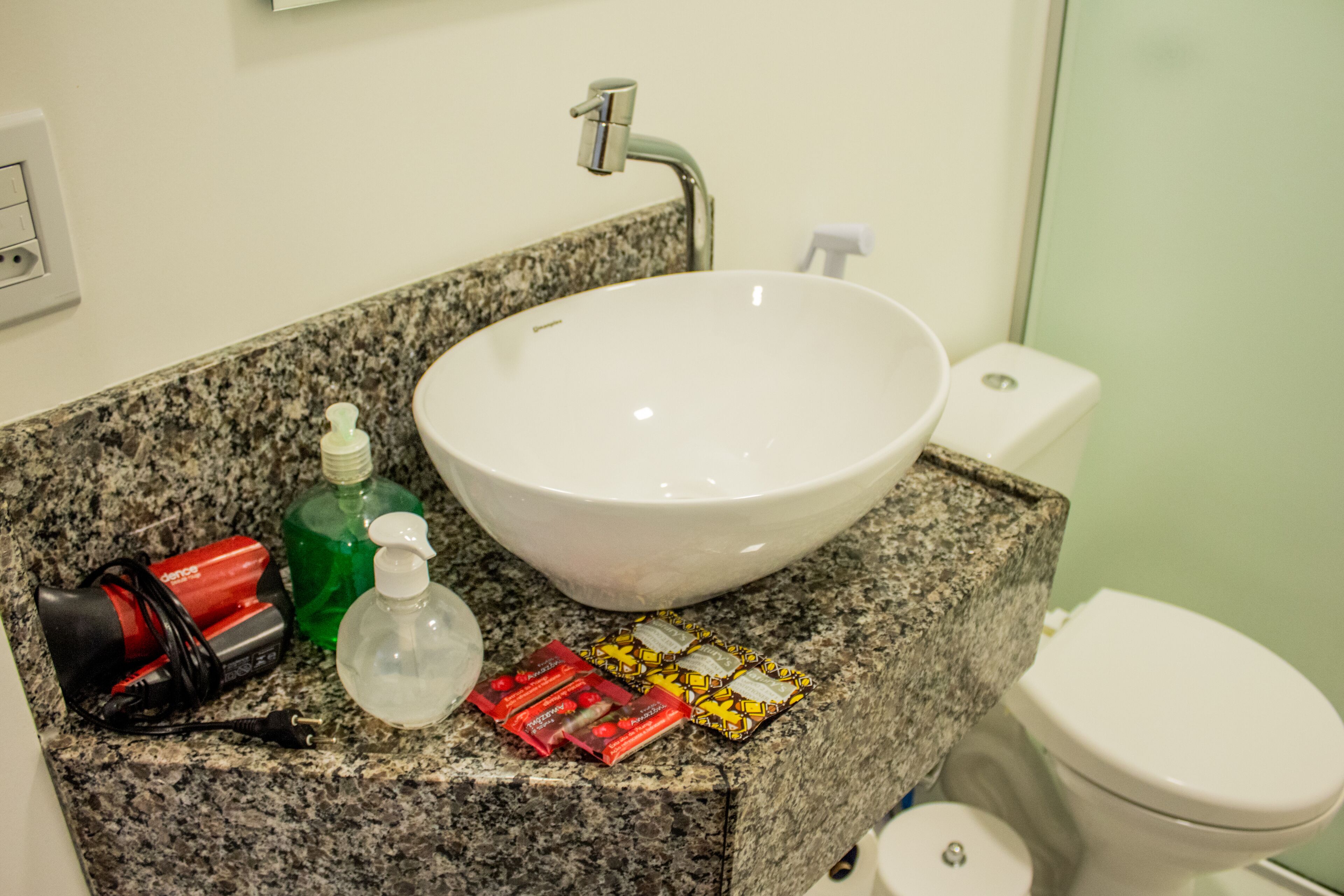 Uma casa de banho com bancada de granito, lavatório branco e sanita.