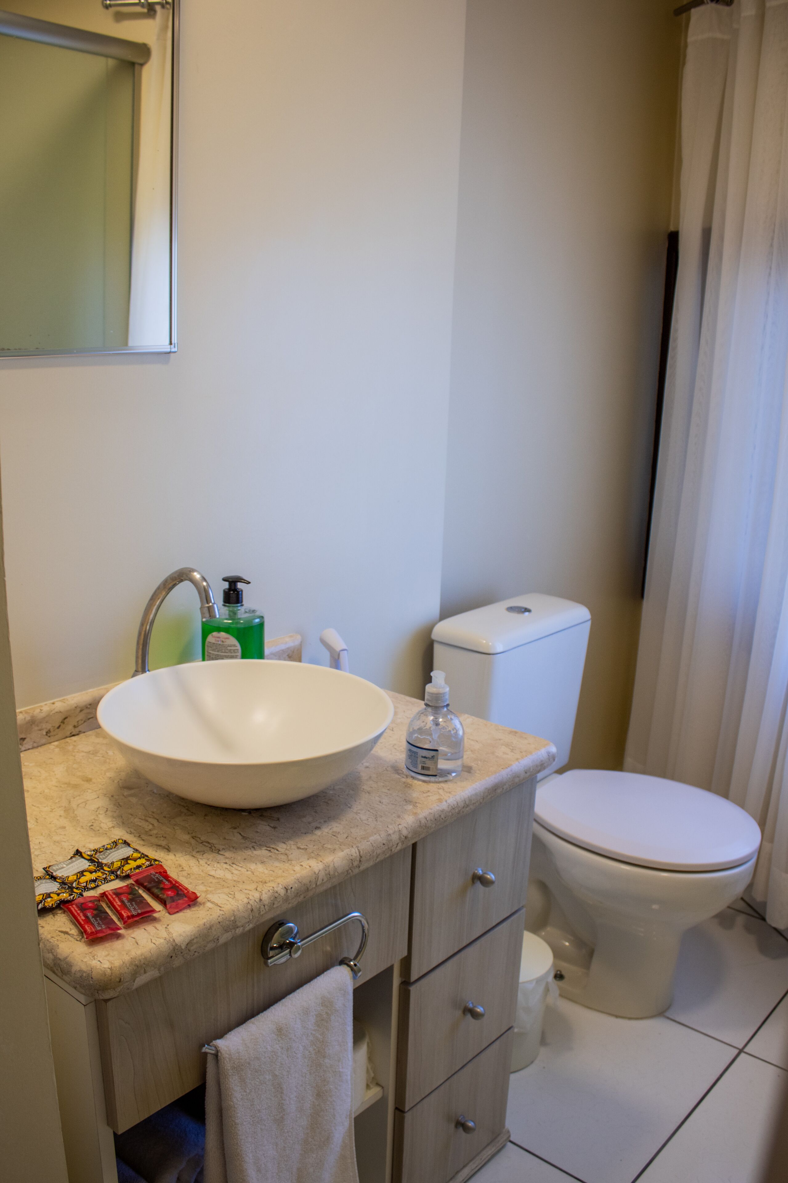 Une salle de bain avec un lavabo blanc, des toilettes et un miroir au-dessus du lavabo.